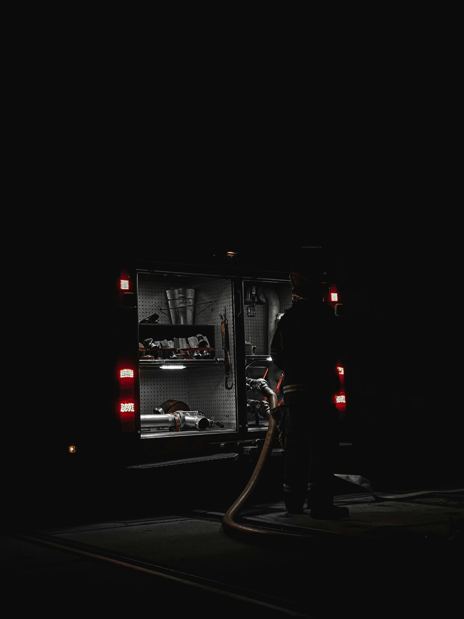 Firefighter and equipment on duty by night near a firetruck.
